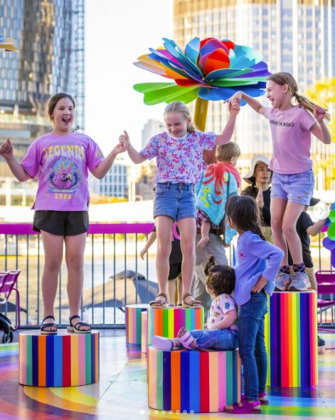 Three girls happily standing on coloured blocks at Brisbane Festival.