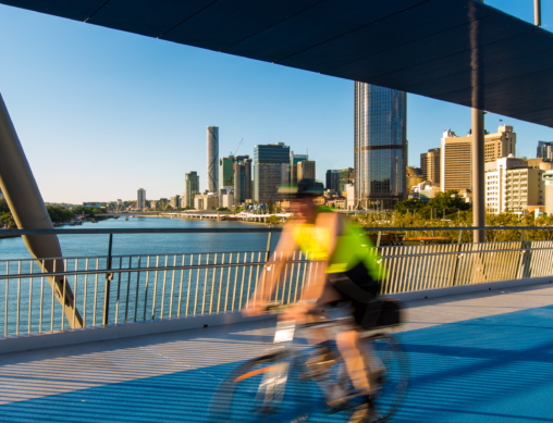 A man riding a bike across a bridge in Brisbane.