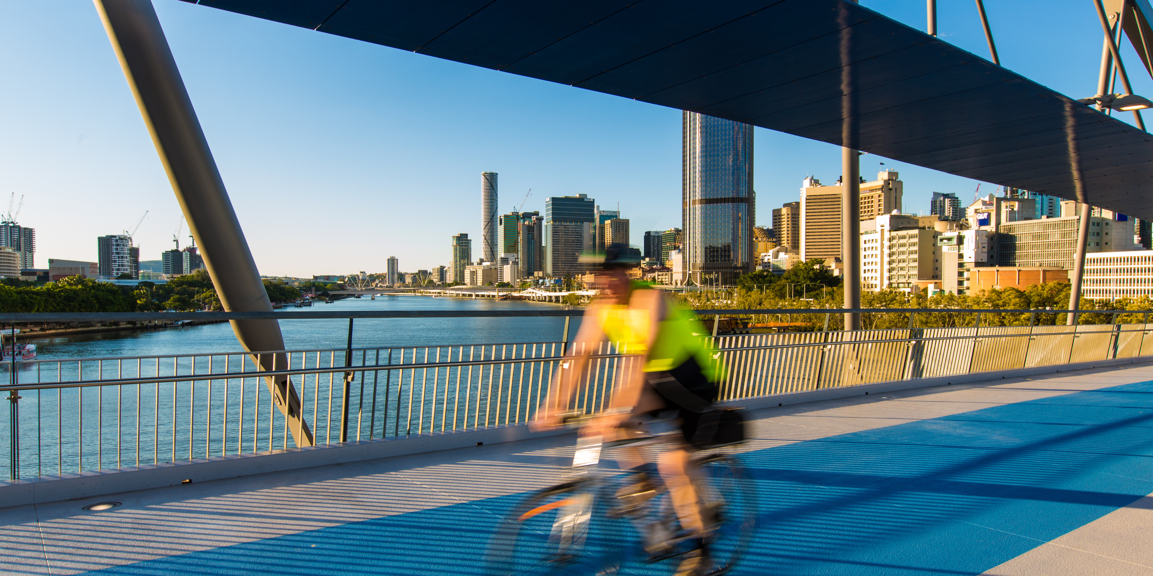 A man riding a bike across a bridge in Brisbane.