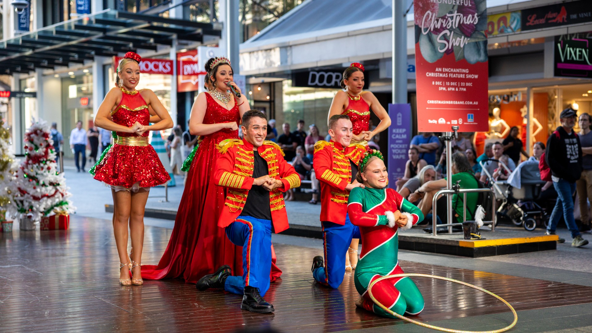 A group of performers dressed in Christmas costumers singing.